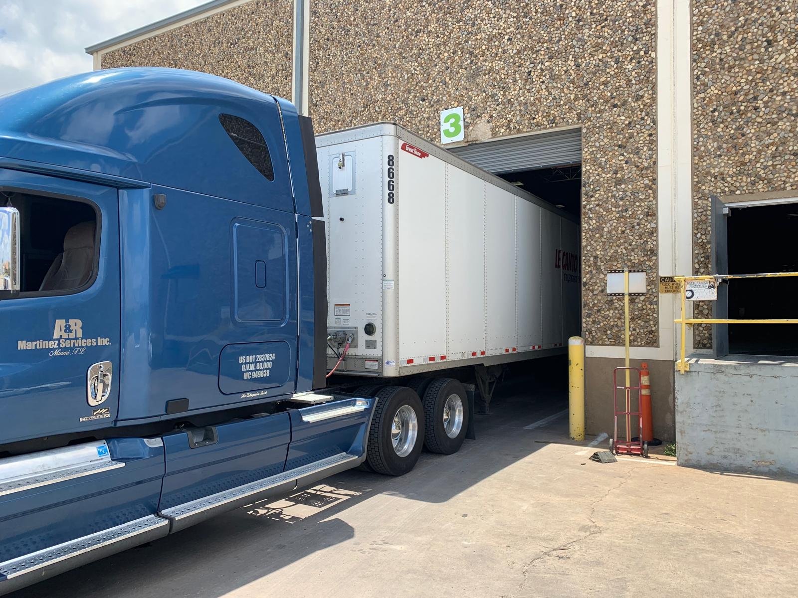 Home Semi truck backing into warehouse loading dock in Miami for freight brokerage and logistics coordination by Dynamic 305 LLC